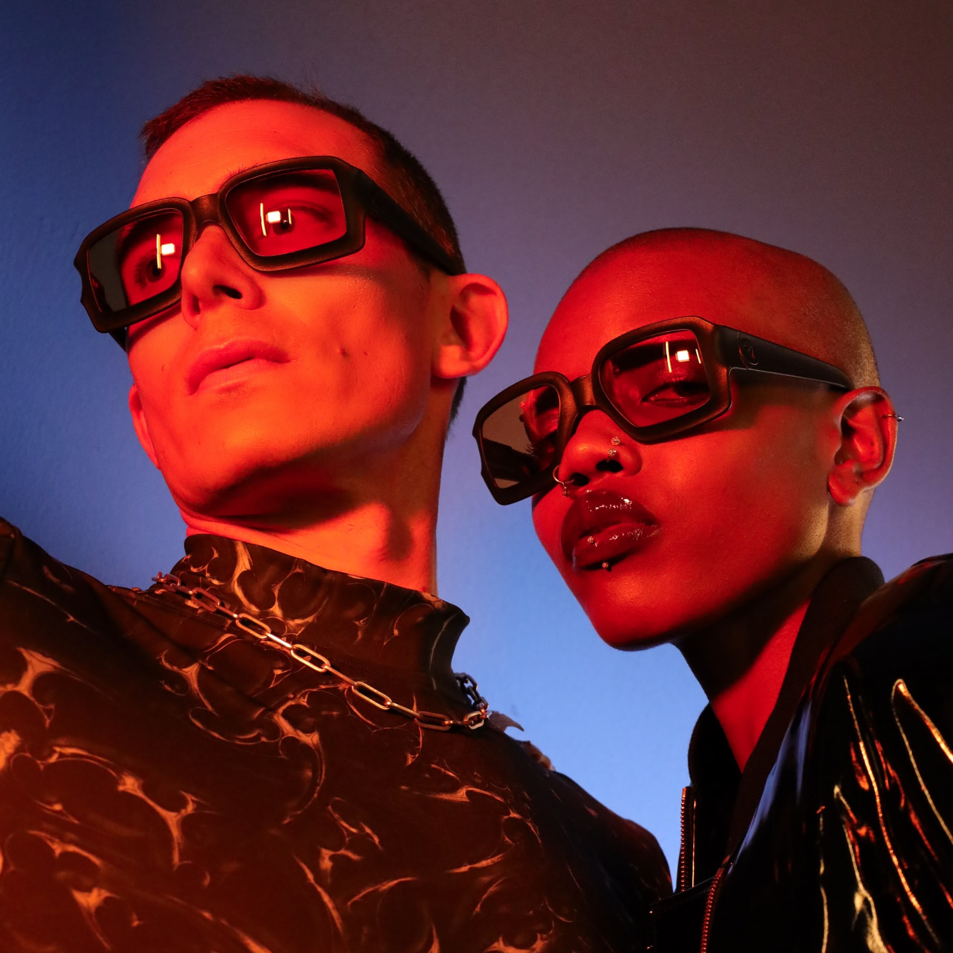 Models wearing REFRAMD Afronaut Eclipse parametric sunglasses in dramatic red studio lighting